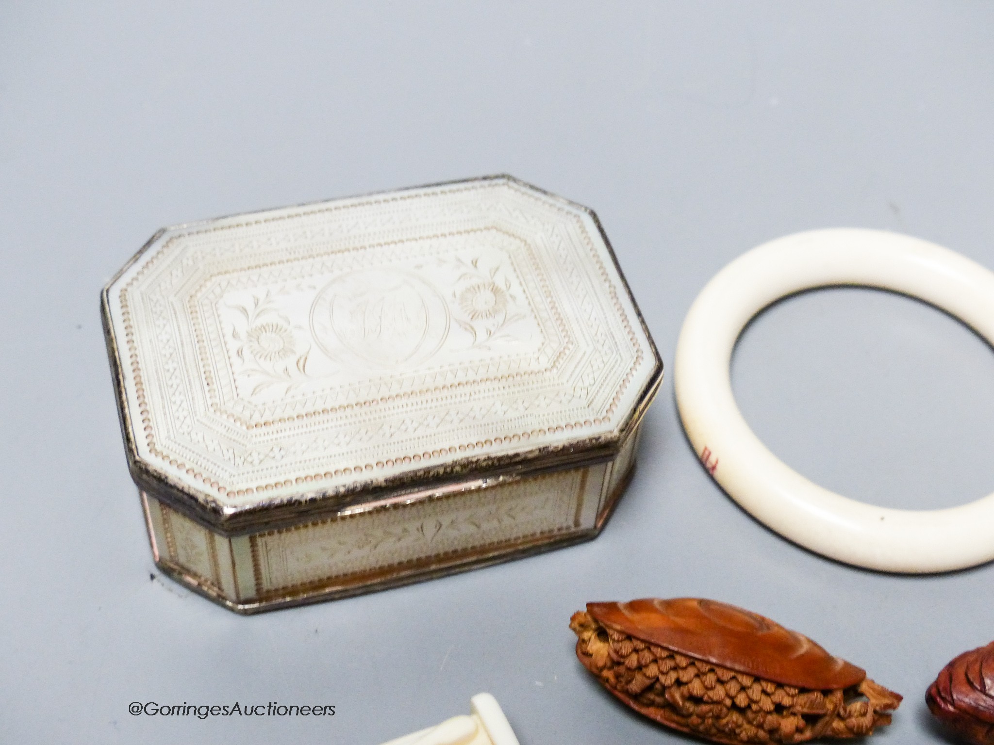 A 19th century panelled mother of pearl box together with a Chinese carved peach stone, a Chinese ivory bangle and a small worked bone multi-tool